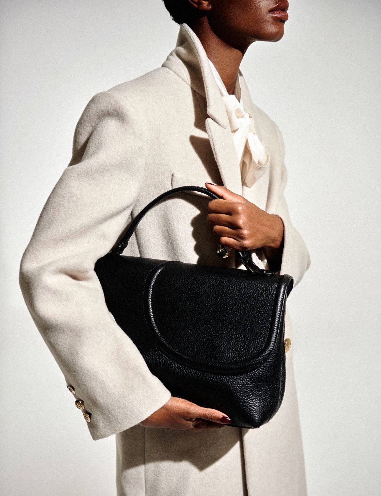 TheHolyBag Tote τσάντα σε μαύρο δέρμα με top handle και αποσπώμενο λουράκι ώμου. Με ασύμμετρο καπάκι. Κλείνει με μαγνήτη και διαθέτει εσωτερική τσέπη.
